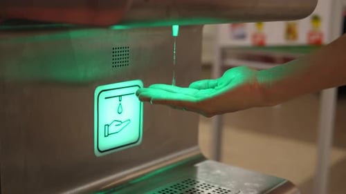 Side View of Person Using Hands Free Sanitizer Dispenser Device in Supermarket