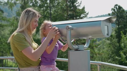 Mother Helps Girl Look Through Binoculars at Resort Deck
