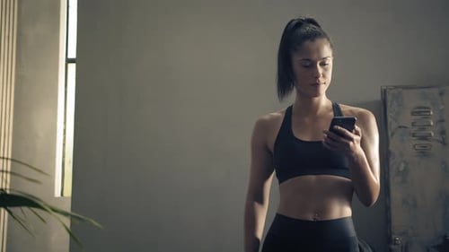 Fit Woman Using Phone after Workout Indoors