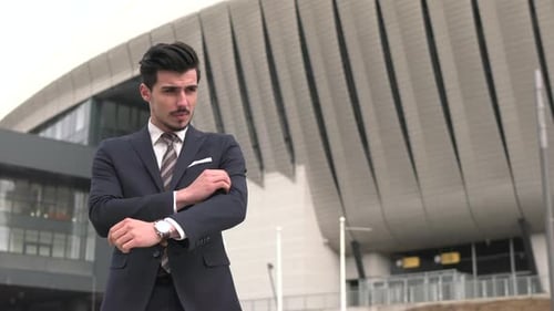 Man Buttons Suit and Crosses Arms in City