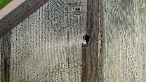 Red tractor plowing field, aerial view in spring