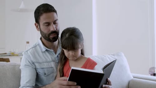Dad and Daughter Reading a Book Together at Home