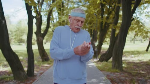 Motivated Sport Athletic Retired Senior Old Man Running in Park Grandfather Checking Pulse on Arm