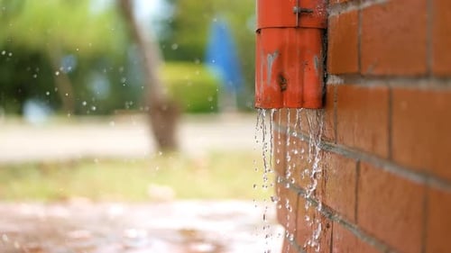 Water Leaking From Damaged Drainpipe on Brick Wall