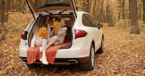 Woman and Child Play with Leaves in Autumn Forest