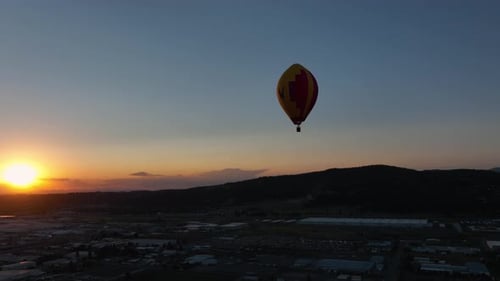 Hot Air Balloon Floating Over Town at Sunrise