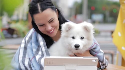 Woman Holding Dog Looking at Tablet Device Outdoors