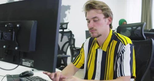 Businessman Working at His Desktop Computer Sitting at His Desk in the Open Space Startup Office