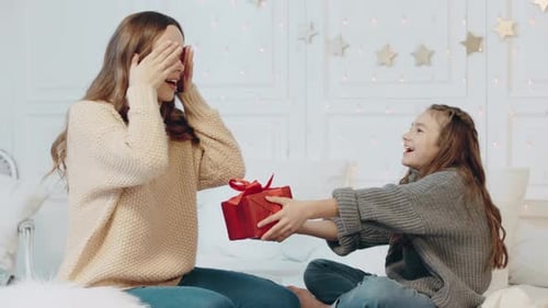 Child Giving Birthday Gift to Woman on Bed