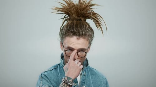 Handsome Man Standing on Grey Background. Stylish Guy Correcting Glasses