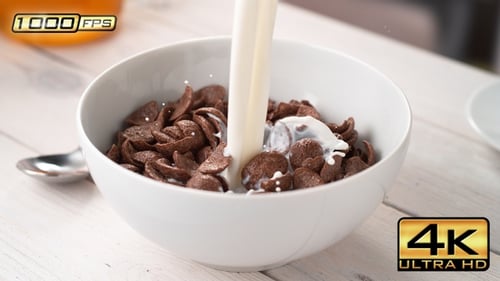 Milk being poured over chocolate cereal in bowl