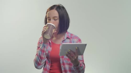 Woman Uses Tablet and Drinks Coffee