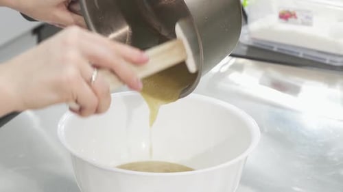 Pouring Golden Liquid Into Bowl in Kitchen