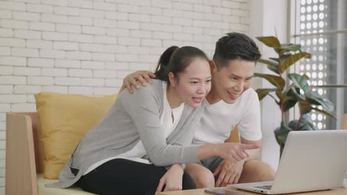 Laughing Couple Looking at Laptop Computer at Home