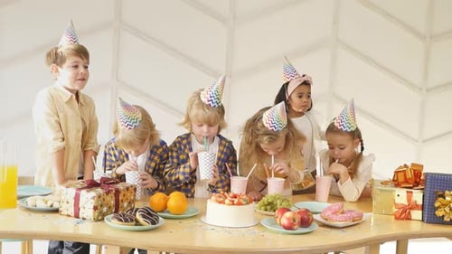 Excited Children Celebrate Birthday Party with Cake and Gifts