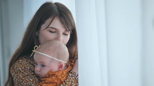 Woman Holds Adorable Baby Near Bright Window