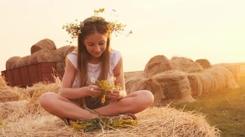 Girl Making Bouquet on Hay Bale at Sunset