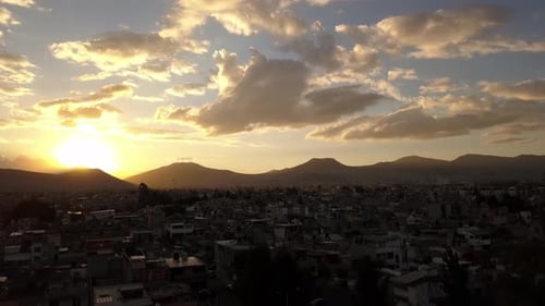 Cloudy aerial drone shot in sunset, Mexico city with mountains