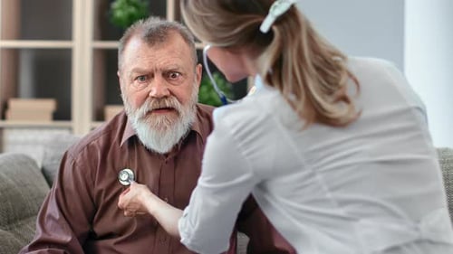 Doctor Listening to Senior Man Heartbeat at Home