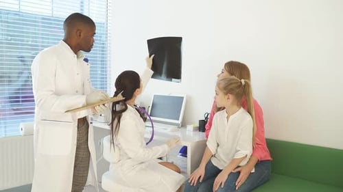 Pediatrician Explaining and Showing Lung Xray for Sick Child and Mother in Hospital Office