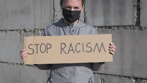 Woman Holding Stop Racism Sign Outdoors