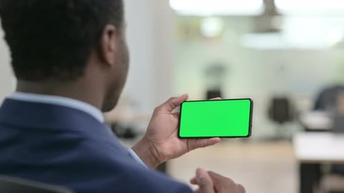 Man Holds Phone with Green Screen in Office
