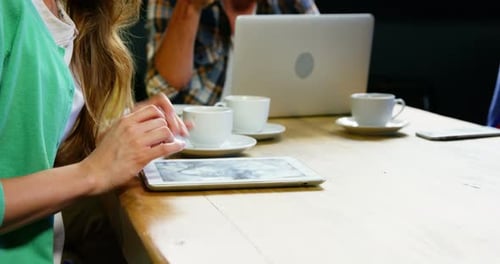 Woman using digital tablet while having coffee