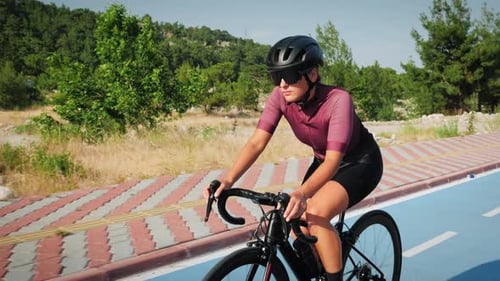 Woman Rides Bicycle on Paved Path