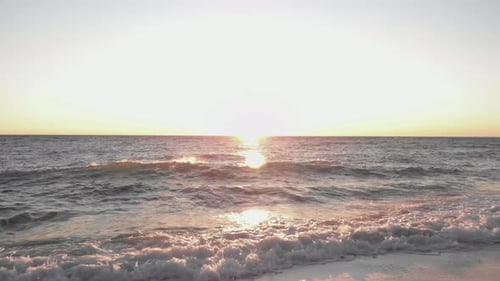 Sea waves splashing and crashing on beach at sunset