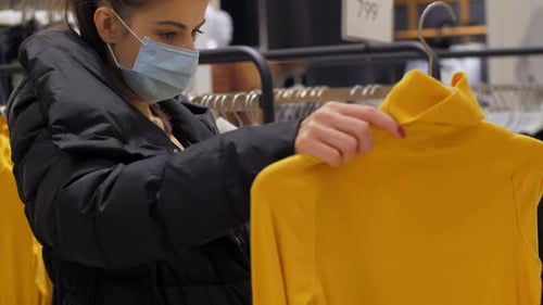 Woman Shops for Clothes Wearing a Face Mask