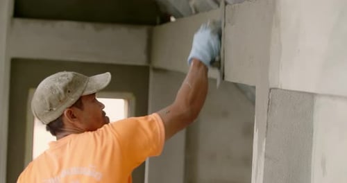 Construction Worker Plasters Wall in Home Interior