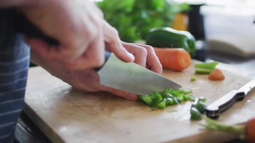 Closeup of mans hand cutting green pepper on the cutting board