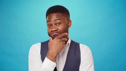 Pensive Man Posing in Front of Blue Background