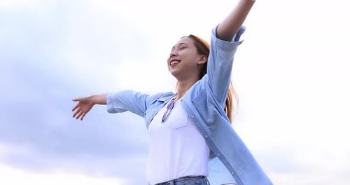 Freedom Asian young woman raising hands on the top at the mountain.
