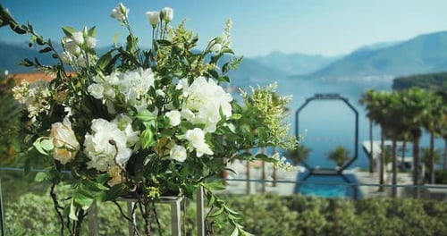Décoration de mariage de bouquets de roses blanches sur la côte avec fond de mer et de montagnes.