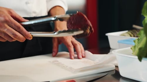 Close-up: The chef puts raw filet mignon on a frying pan