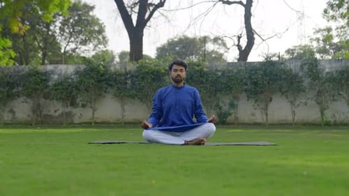 Man Meditating in Lotus Position Outdoors on Yoga Mat