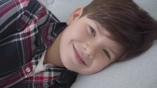 Close-up of Caucasian Boy with Brown Hair and Grey Eyes Looking at Camera and Smiling. Happy Child