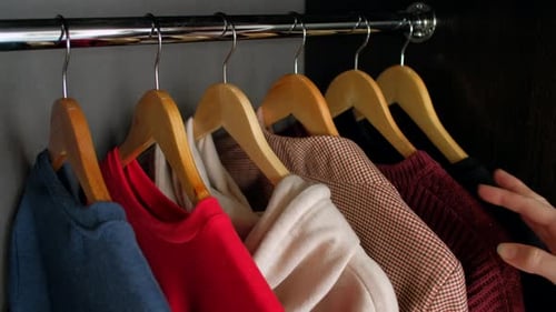 Hand Selecting Clothes in a Closet