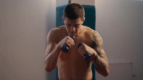 Muscular Man Boxing with Dumbbells in Gym