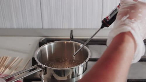 Chef Checks the Temperature of the Caramel in the Pot