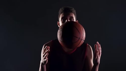 Porträt eines jungen afroamerikanischen Basketballspielers in einem dunklen Studio auf schwarzem Hintergrund