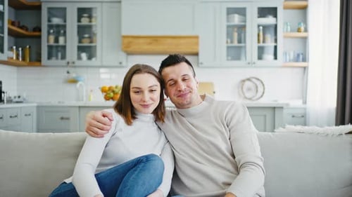 Close Up of Happy Man and Woman Sitting on Sofa at Home and Smiling to Camera Bonding to Each Other