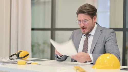 Middle Aged Engineer Reacting to Loss while Reading Documents in Office