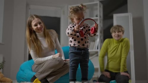 Toddler Puts on Headphones Watched by Family