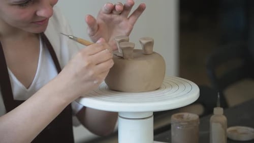 Close Up of Female Hands Holding Stick and Making Ornament on Earthenware. Clay Master Moulding Clay