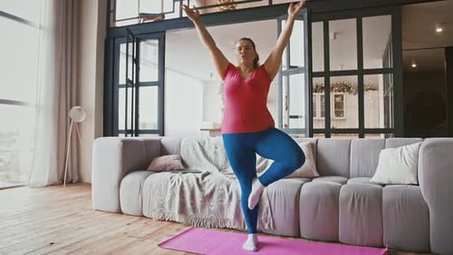 Young Attractive Plus Size Woman Practicing Yoga in Static Tree Pose at Home Hands in Namaste