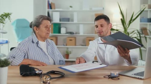 Doctor Explains Report to Senior Woman in Office