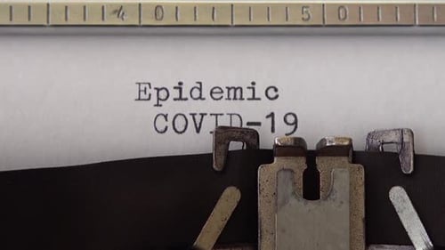 Typing phrase Epidemic COVID-19 on retro typewriter. Close up.