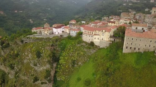 Aerial View Drone Flies Over Medieval Village on Hill Overlooking Misty Mountain Gorge